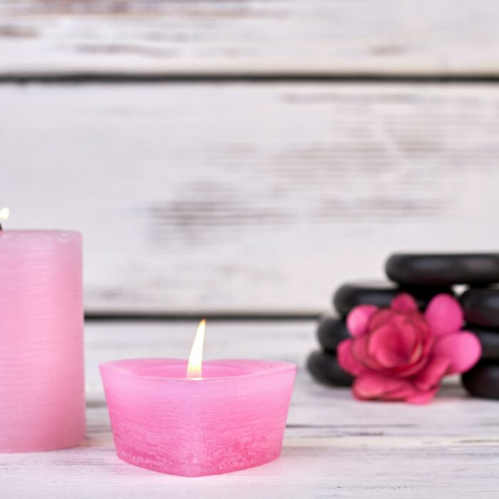 Pink wax candles with stones and flower for spa.